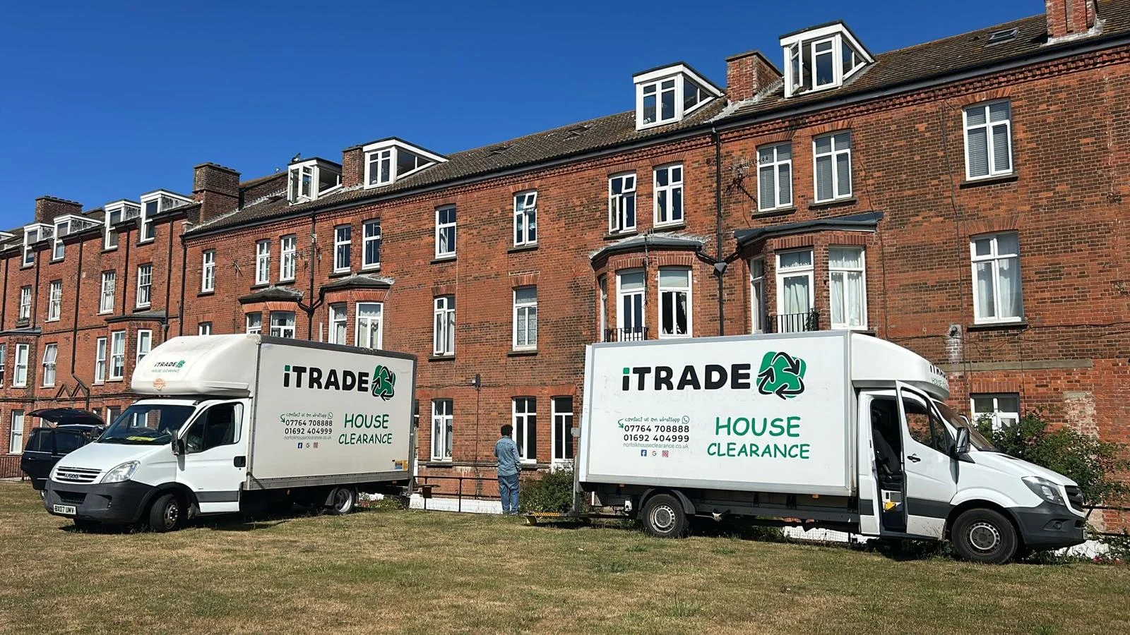 Two iTrade house-clearance vehicles outside a red-brick residential building