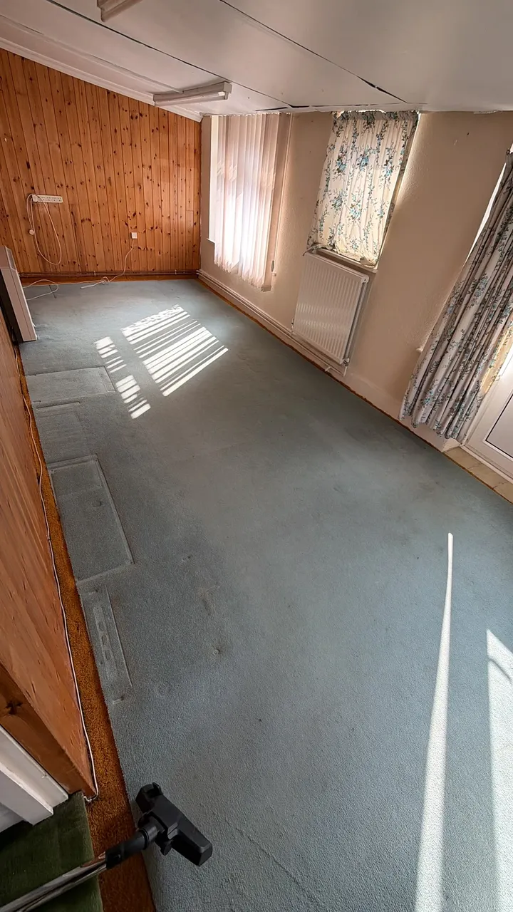 Cleared room with timber wall panelling, a grey carpet and a radiator