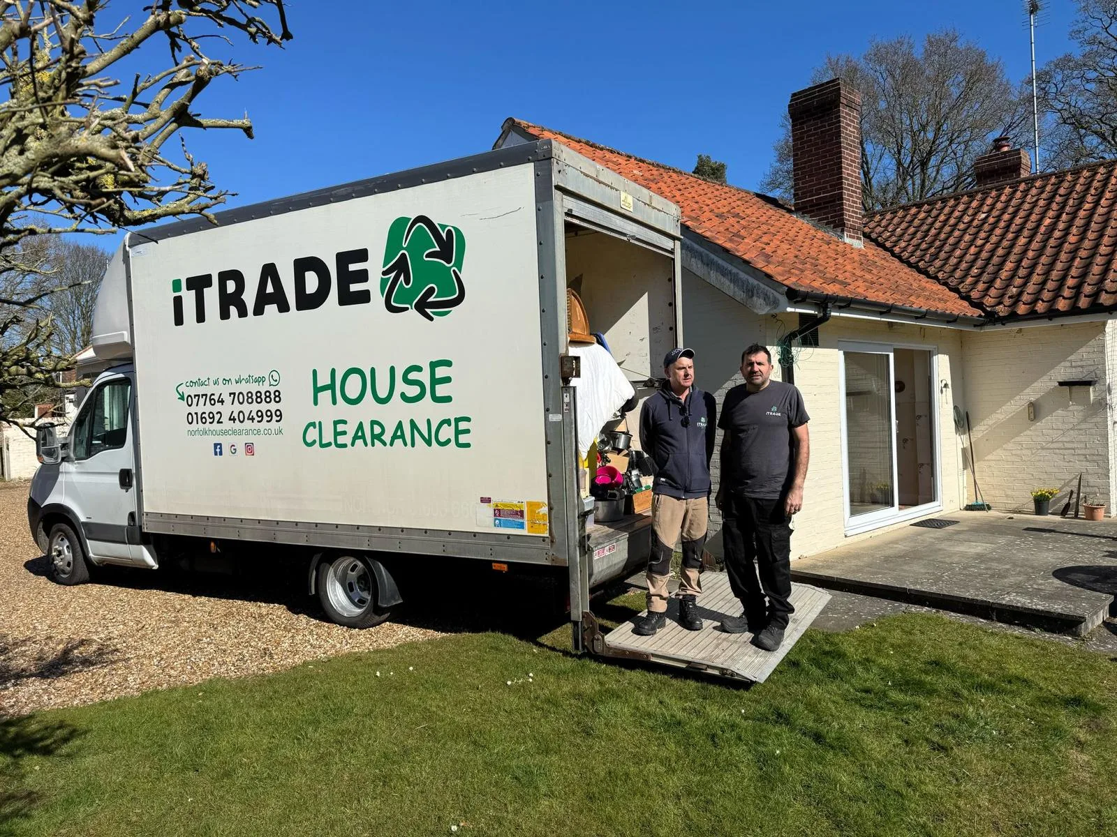 Two iTrade team members beside an open clearance vehicle at a residential property